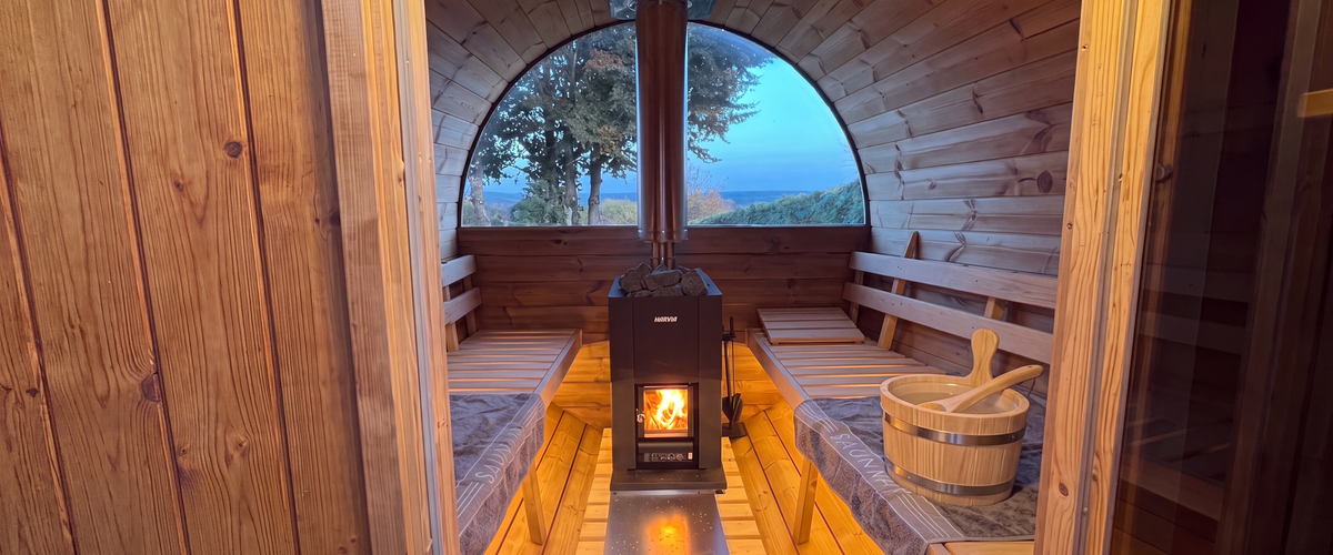 Brennender Holzofen in der Sauna mit Blick auf die Saunasteine
